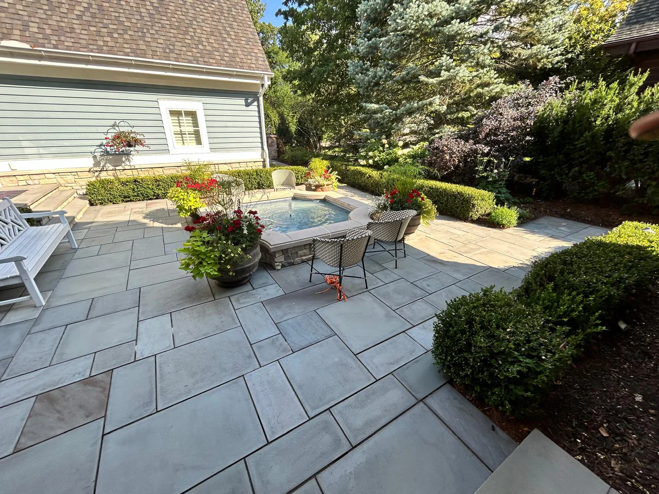 Completed bluestone patio adjacent to lawn and landscaping