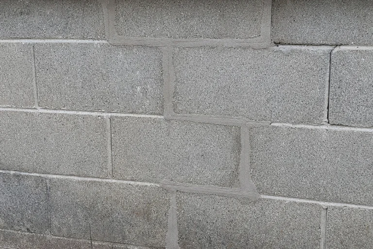 Concrete block wall with a localized matched-mortar repair and coherent bed and head joints